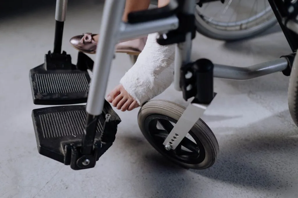 Person using a wheelchair with a foot cast during accident recovery at home after a lower leg injury