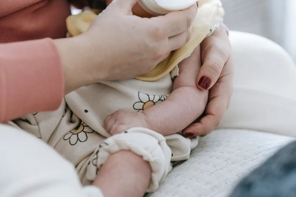 Parent feeding infant with a bottle, illustrating baby nutrition and development during early growth stages