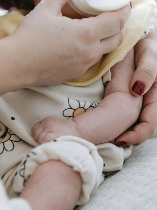 Parent feeding infant with a bottle, illustrating baby nutrition and development during early growth stages