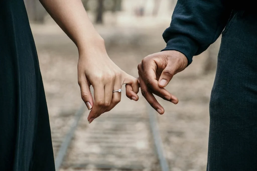 Close-up of a couple holding hands with an engagement ring visible, symbolizing love, commitment, and emotional support during fertility challenges.