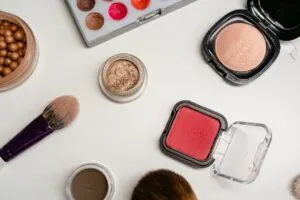 Flat lay of assorted cosmetic products including blush, highlighter, bronzing pearls, and makeup brushes, representing how to build a premium cosmetic brand through cohesive product presentation.