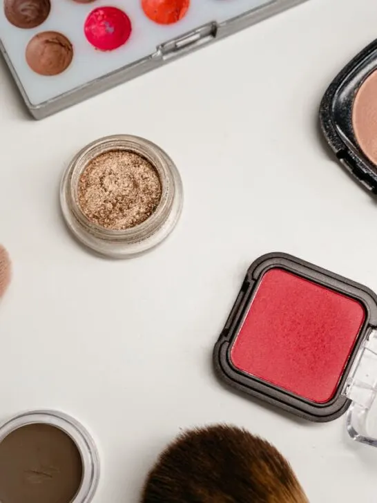 Flat lay of assorted cosmetic products including blush, highlighter, bronzing pearls, and makeup brushes, representing how to build a premium cosmetic brand through cohesive product presentation.