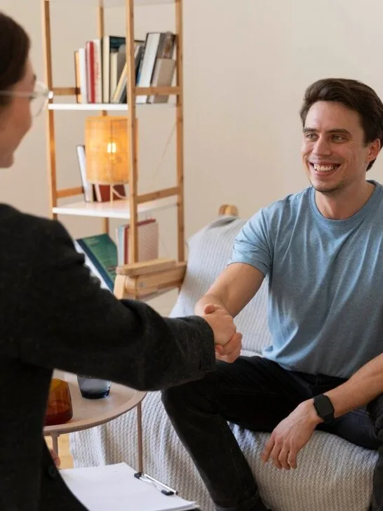Therapist and client shaking hands during a counseling session in a comfortable office setting