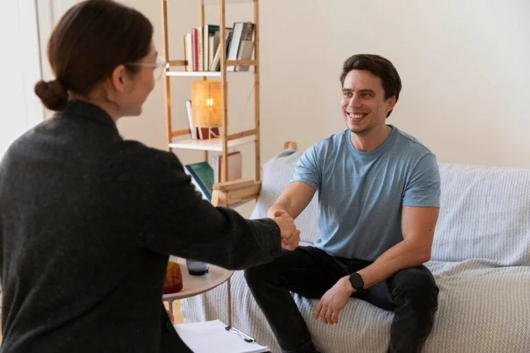 Therapist and client shaking hands during a counseling session in a comfortable office setting