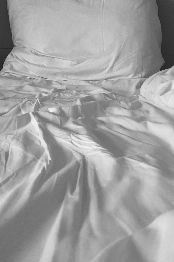Soft white bed sheets spread across a mattress, showing texture and fabric comfort