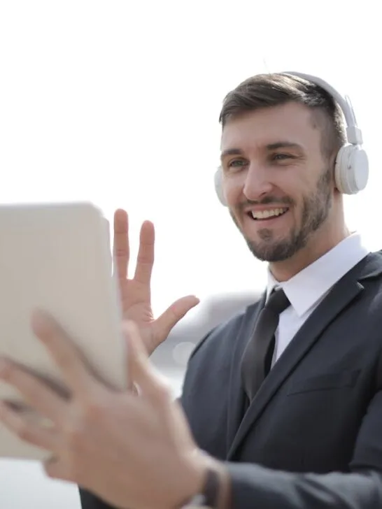 Professional businessman using a tablet and wireless headset during a video call, representing virtual voice systems for business in action.