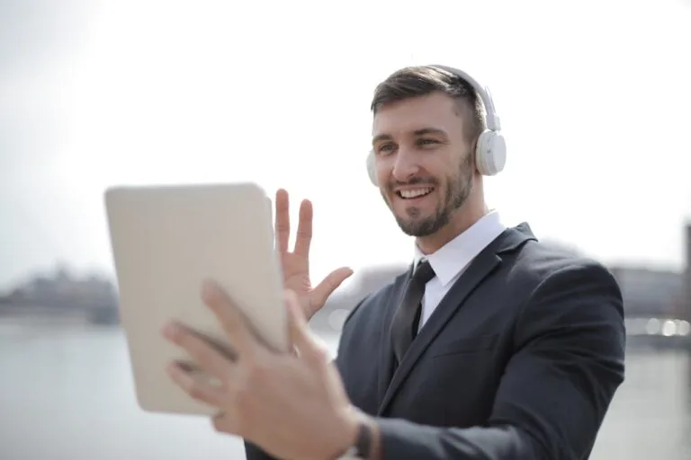 Professional businessman using a tablet and wireless headset during a video call, representing virtual voice systems for business in action.