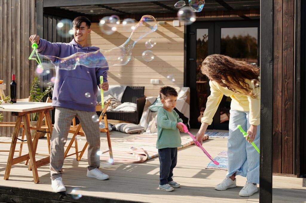 family enjoying outdoor patio with bubbles, child playing, and parents relaxing in backyard space