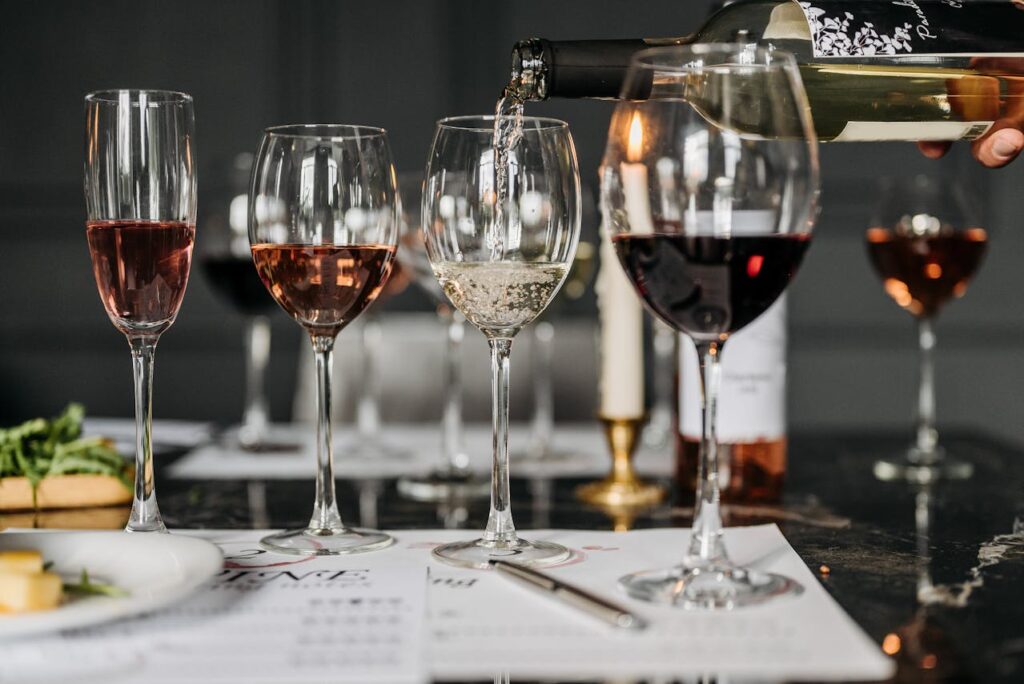 Multiple glasses of red, white, and ros&eacute; wine lined up during a wine tasting, illustrating how to taste wine and compare different flavors