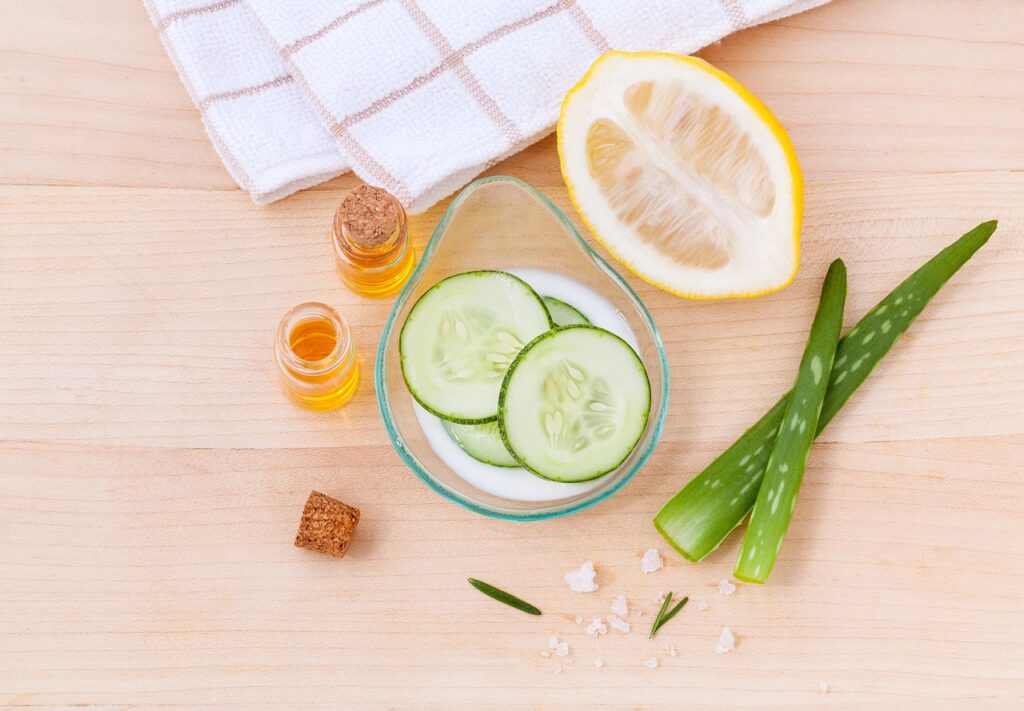 How natural skincare ingredients support skin health with cucumber slices, aloe vera, lemon, and nourishing oils on a wooden surface
