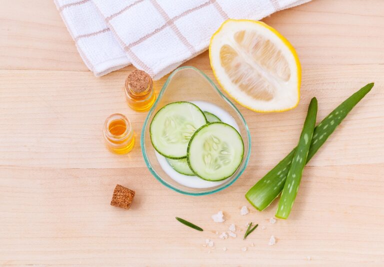 how natural ingredients support skin health with cucumber slices, aloe vera, lemon, and nourishing oils on a wooden surface
