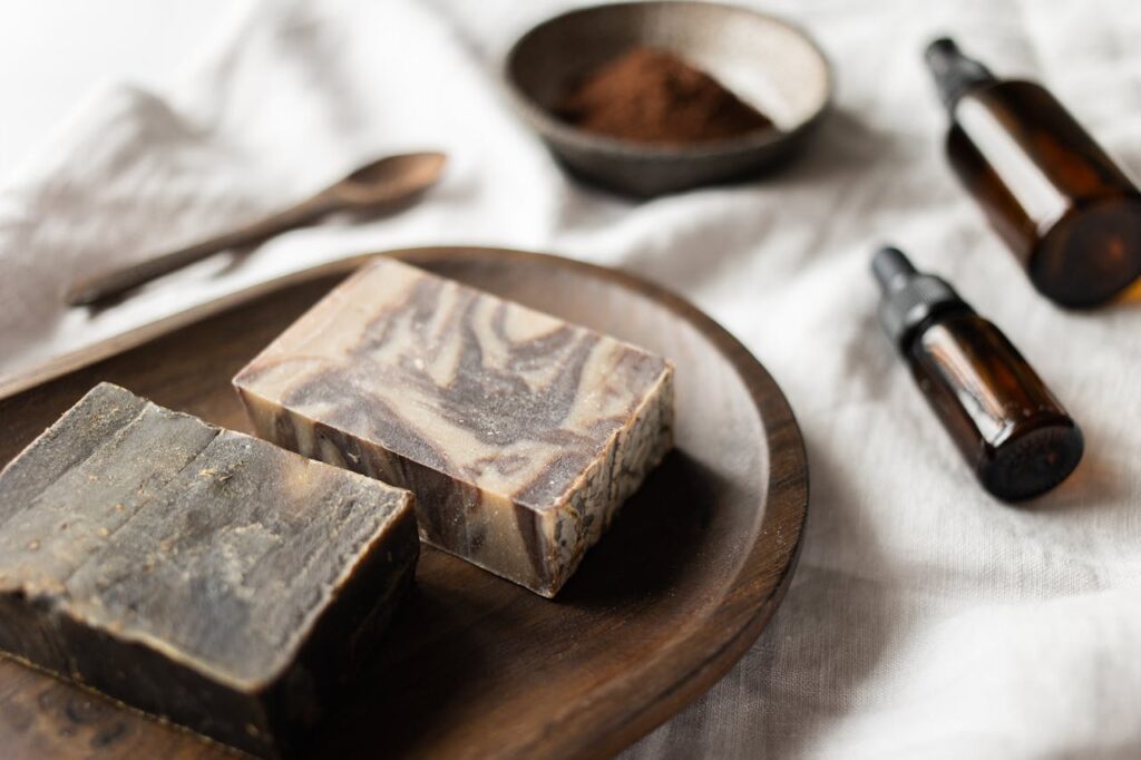 handmade natural soap bars with essential oil bottles and wooden tray in a soft neutral setting
