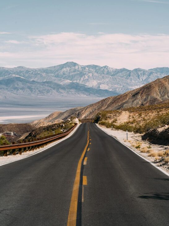 Mountain highway winding through desert hills and distant peaks, capturing the beauty of scenic road trips through wide natural landscapes.