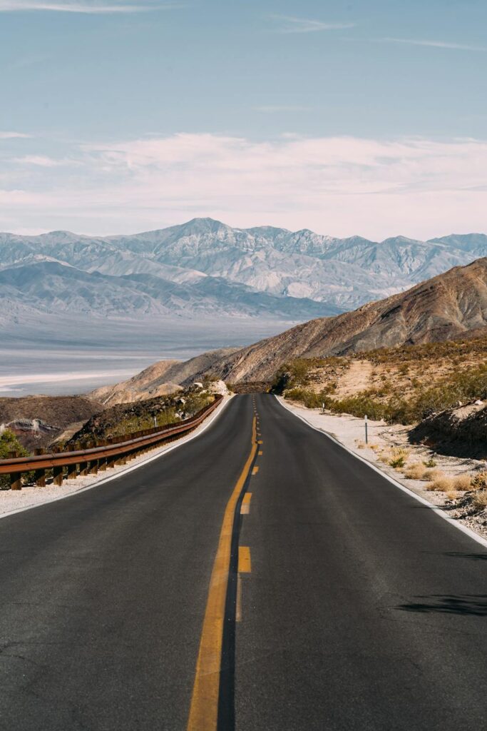 Mountain highway winding through desert hills and distant peaks, capturing the beauty of scenic road trips through wide natural landscapes.