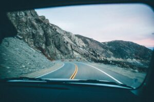 Winding mountain highway viewed from inside a car during a scenic road trip through rugged terrain.