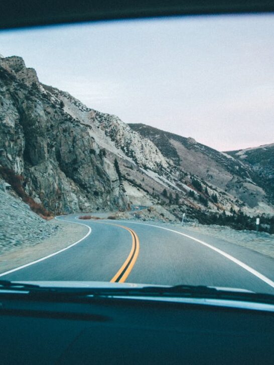 Winding mountain highway viewed from inside a car during a scenic road trip through rugged terrain.