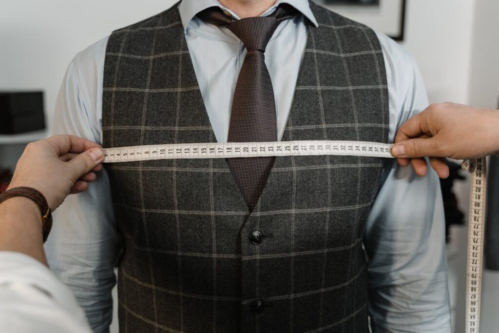 Tailor measuring a client&rsquo;s chest during a fitting to demonstrate what to look for when buying a custom suit.
