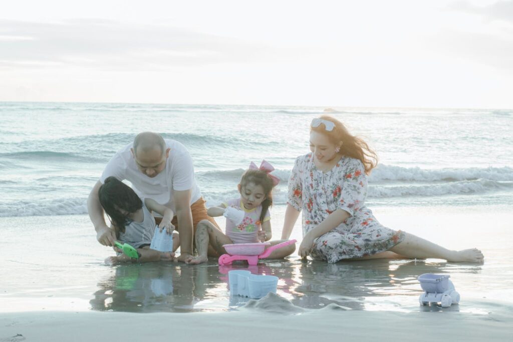 Family enjoying a Florida family vacation while playing in the sand by the ocean at sunset