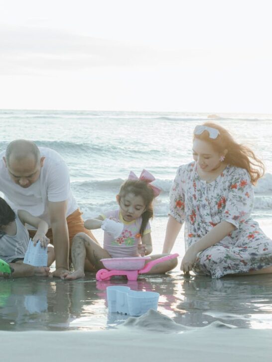 Family enjoying a Florida family vacation while playing in the sand by the ocean at sunset