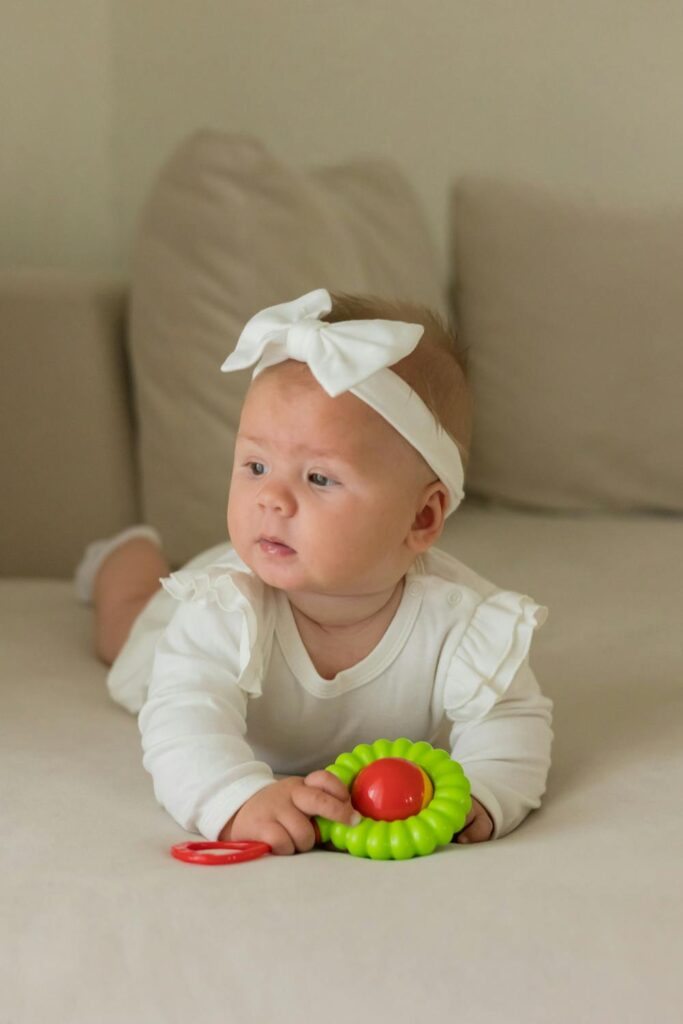 Baby girl playing with toy on bed in a soft, cozy home setting