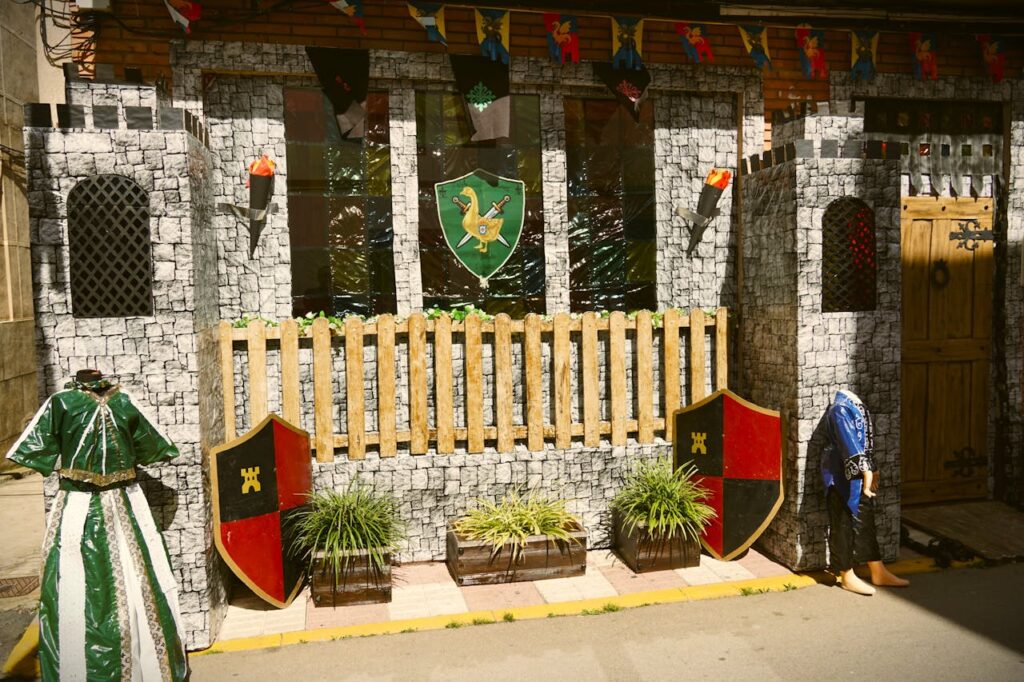 Renaissance party ideas featuring DIY medieval castle backdrop with shields, banners, and themed decorations for a festive setup