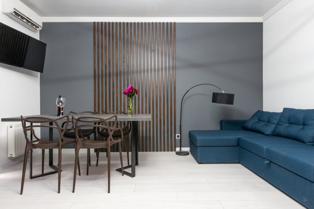 Modern dining and living area with a gray accent wall and vertical wood slat design behind a table and chairs