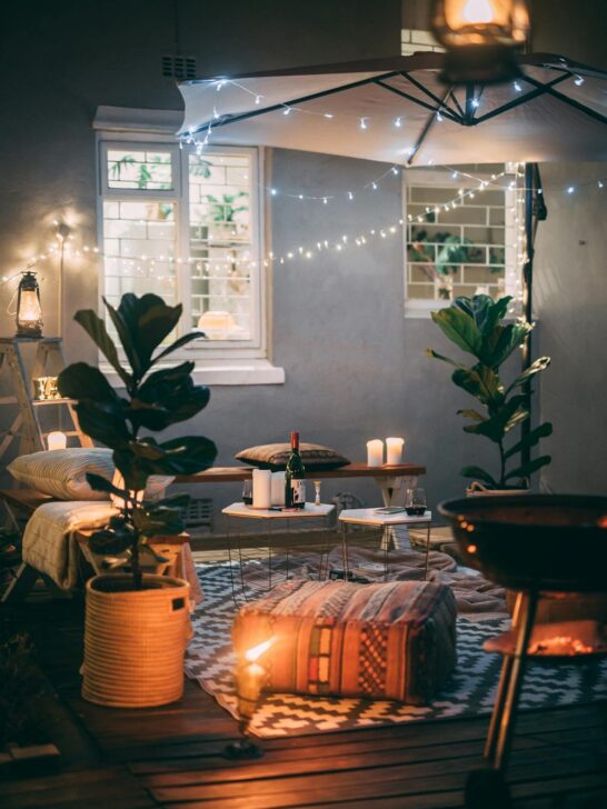 Cozy outdoor patio setup with string lights, candles, and seating area showing relaxing backyard wellness ideas at night
