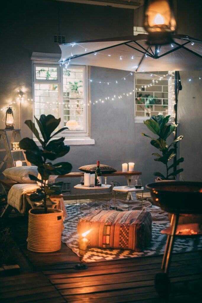 Cozy outdoor patio setup with string lights, candles, and seating area showing relaxing backyard wellness ideas at night