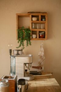 Cozy home coffee station with espresso machine, wooden shelves, and neatly arranged mugs and decor