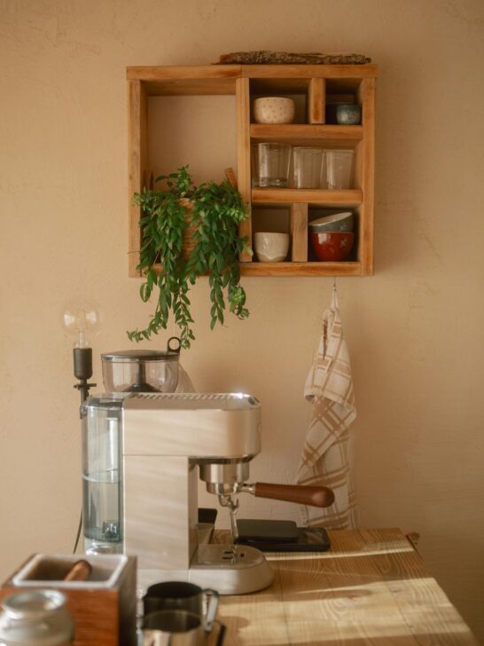 Cozy home coffee station with espresso machine, wooden shelves, and neatly arranged mugs and decor