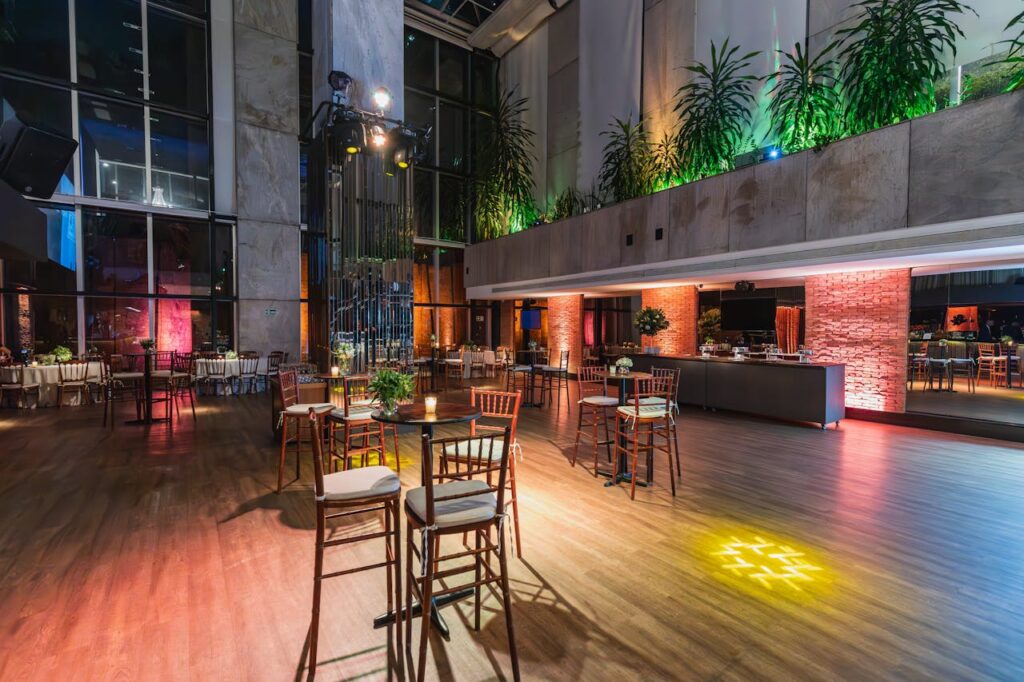 Modern indoor event venue with cocktail tables, warm lighting, and open floor space for guests to mingle comfortably