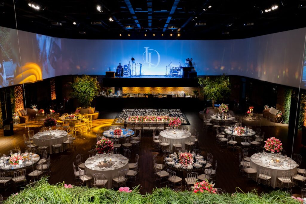Elegant banquet setup with round tables, floral centerpieces, and stage lighting, showcasing event planning tips for a polished event layout