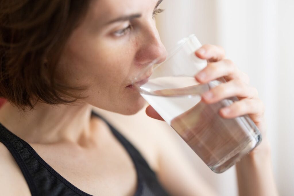 Woman drinking water from a glass, highlighting hydration and simple wellness routines