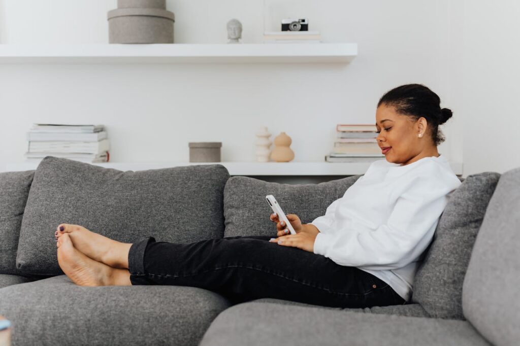 Woman relaxing on a sofa using her phone in a calm, comfortable home environment
