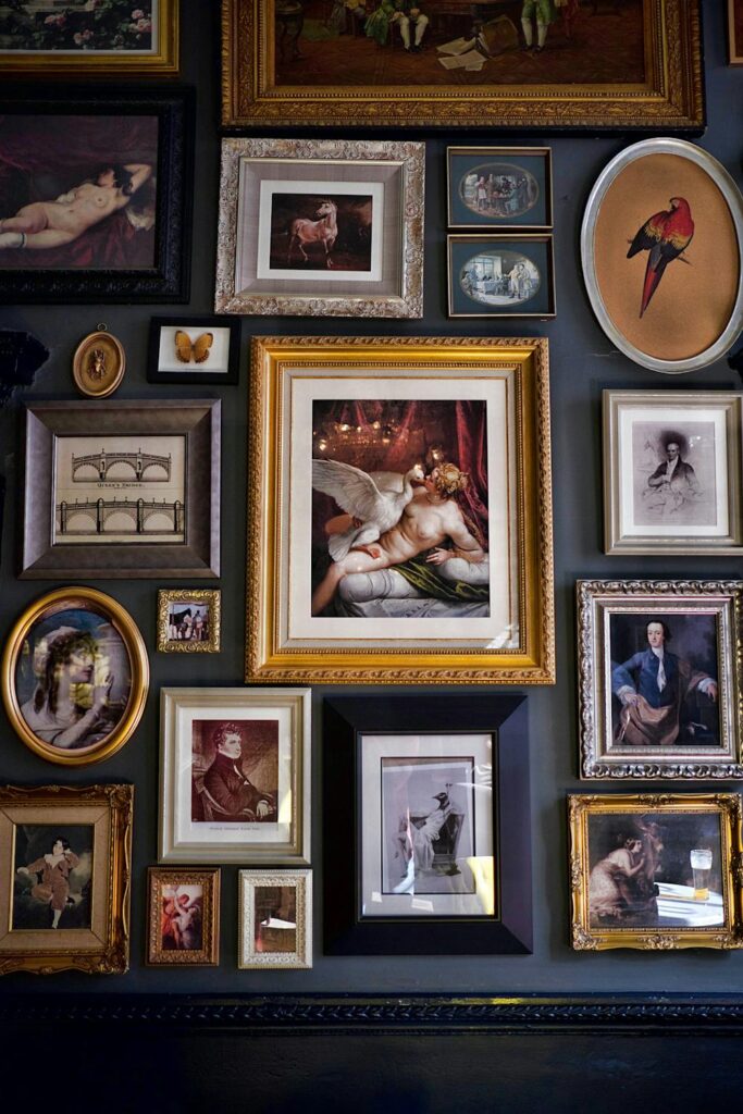 Eclectic gallery wall with vintage artwork and mixed frame styles on a dark wall