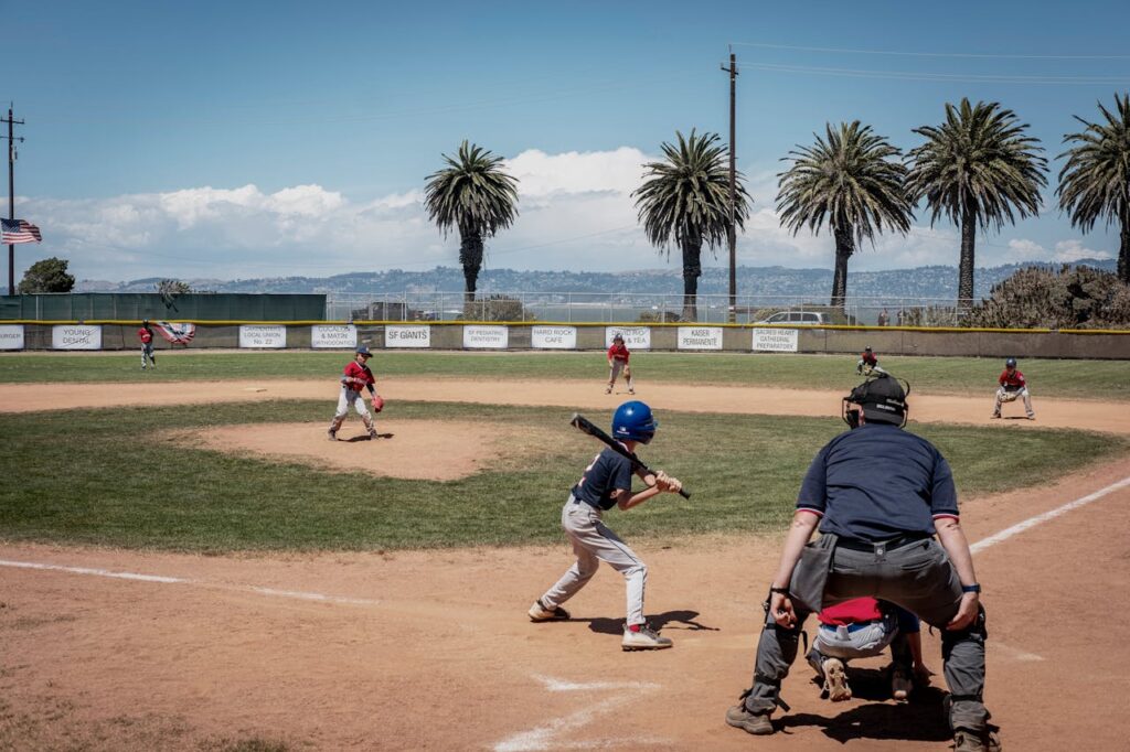 Youth baseball game in progress with players on the field and a batter at home plate