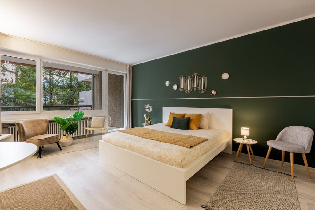 Bedroom with green accent wall, neutral bedding, and modern furniture creating a cozy and stylish space