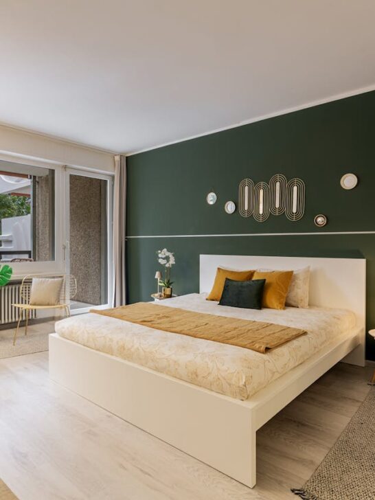 Bedroom with green accent wall, neutral bedding, and modern furniture creating a cozy and stylish space