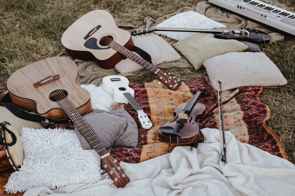 how to play an instrument for beginners with acoustic guitars, ukulele, and violin set up for practice outdoors