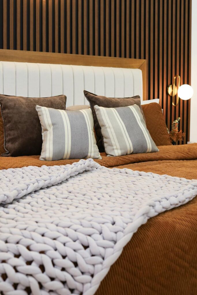 Stylish guest room bed with textured blanket and neutral pillows designed for comfort and relaxation