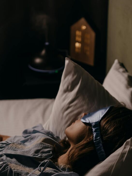 Woman wearing a sleep mask resting in bed showing how to relax before bed with a calm nighttime routine