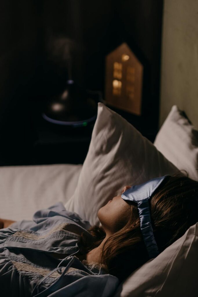 Woman wearing a sleep mask resting in bed showing how to relax before bed with a calm nighttime routine
