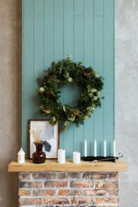 Decorated mantel with greenery wreath, candles, and framed art creating a warm and seasonal focal point