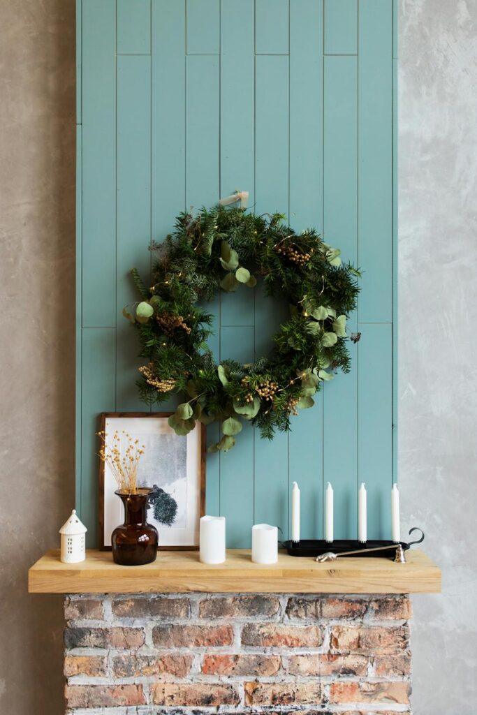 Decorated mantel with greenery wreath, candles, and framed art creating a warm and seasonal focal point