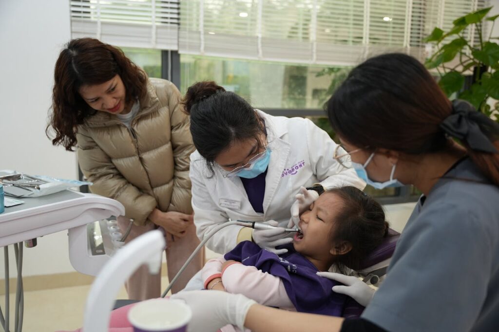 Child receiving a dental checkup from a modern family dentist while a parent looks on in a bright clinic