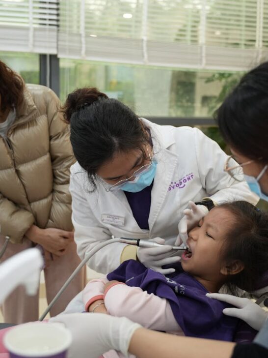 Child receiving a dental checkup from a modern family dentist while a parent looks on in a bright clinic