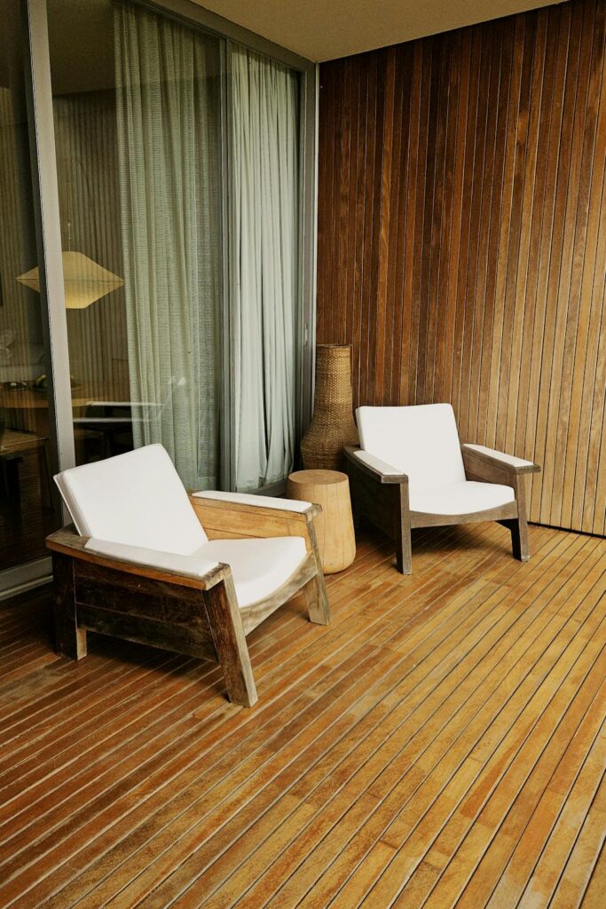Wooden outdoor chairs on a covered deck showing patio furniture that lasts through changing weather conditions