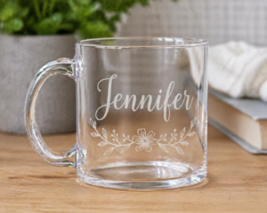 Clear acrylic mug engraved with the name Jennifer and a delicate floral design on a wooden surface