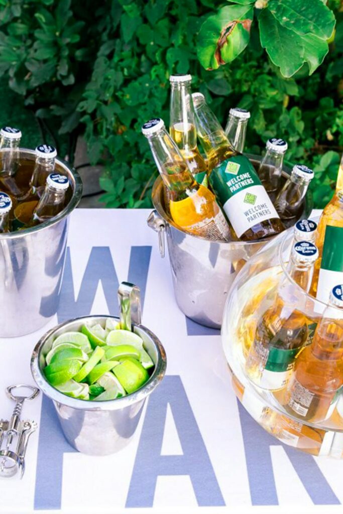 Outdoor drink station with bottled beverages on ice, fresh lime wedges, and a simple setup for stress-free hosting tips