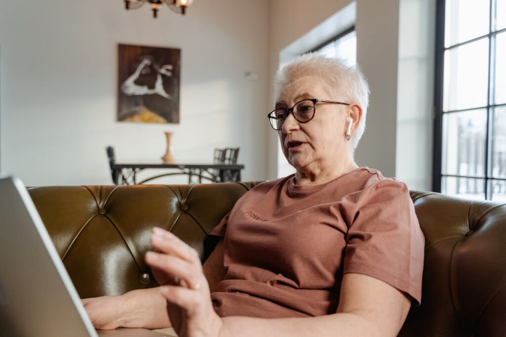 Elderly woman using a laptop at home during a video call for family communication and support